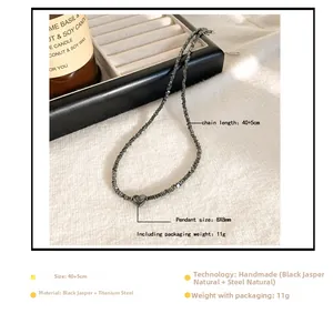 Detail van de handgemaakte kralenketting met zwarte stenen en een stalen hartje