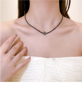 Detailopname van de elegante zwarte klaver hanger ketting gedragen op het sleutelbeen