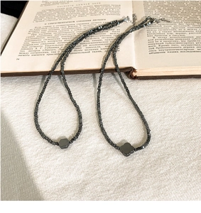Detail van zwarte kralenkettingen met klaver- en zeshoekige hangers op vintage boek