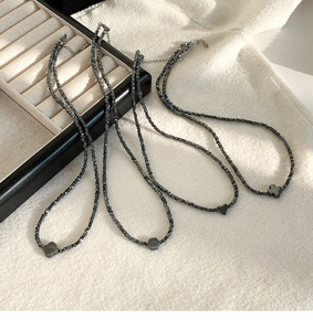 Detail van zwarte stenen kettingen met klaver- en hartvormige hangers op leer
