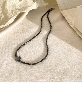 Detail van titanium stalen kralenketting met zwart kruis hangertje op esthetische basis