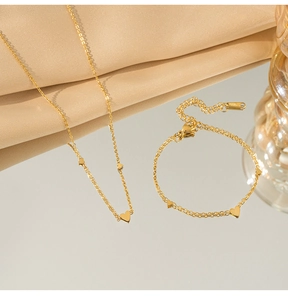 Vista dettagliata del set collana e bracciale con cuore d'oro su seta con riflesso a specchio