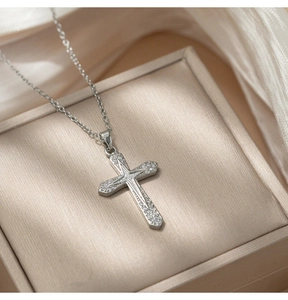 Macro shot of silver cross necklace with pavé zircons in a champagne velvet box