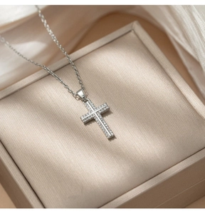 Macro shot of silver crystal cross pendant on silk for elegant luxury jewelry detail