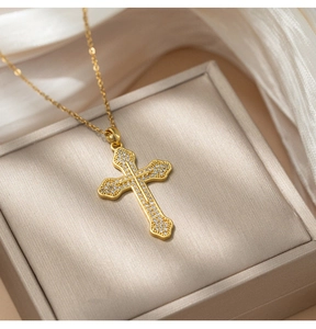 Detail of gold titanium cross necklace with sparkling crystals on a jewelry box