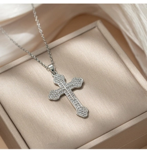Close-up of sparkling crystal cross pendant on silk lining with elegant silver chain