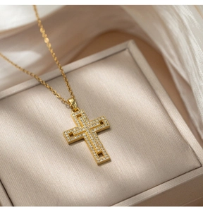 Detailed macro view of gold cross pendant with pavé diamonds on elegant satin fabric