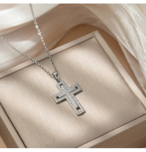 Macro shot of silver cross pendant with micro-pave crystals in a luxury jewelry box