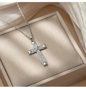 Detail of silver cross pendant with heart tips and pave-set cubic zirconia on satin