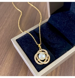 Détail d'un collier camélia doré avec perles et zircons dans un écrin à bijoux