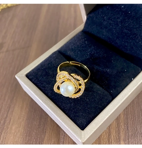 Gros plan sur la bague camélia dorée avec perle blanche et détails en zircone cubique