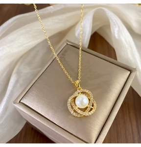 Gros plan du pendentif en perle avec cristaux pavés sur une chaîne dorée et coffret