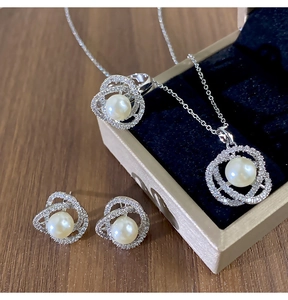 Gros plan d'un ensemble de bijoux camélia avec perles et zircons en boîte dorée