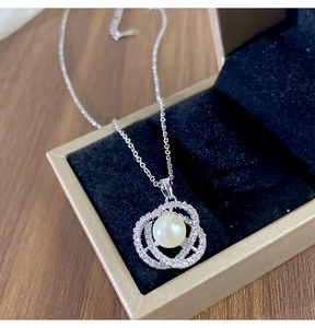 Détail macro du pendentif perle camélia serti de zircons cubiques sur doublure soyeuse