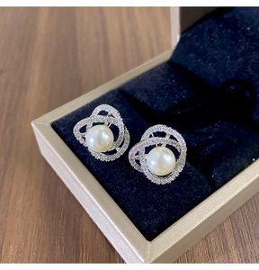 Détail de boucles d'oreilles camélia avec perle blanche et zircon dans un écrin à bijoux