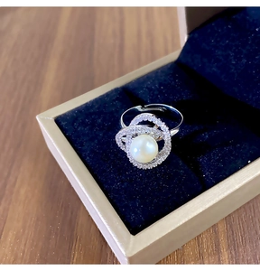 Détail macro d'une bague perle camélia avec zircons et anneau argenté réglable