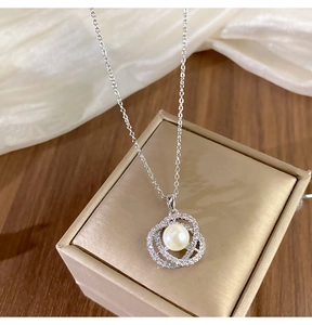 Détail macro d'un pendentif perle camélia avec zircons sur une chaîne en argent fin