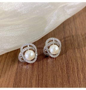 Gros plan sur les boucles d'oreilles perles camélia et oxydes de zirconium sur bois