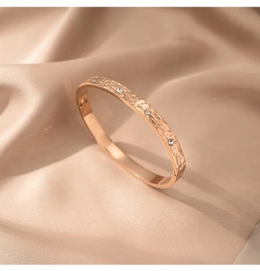 Detailansicht des roségoldenen Hammerschlag-Armreifs mit Strass auf Champagner-Seide