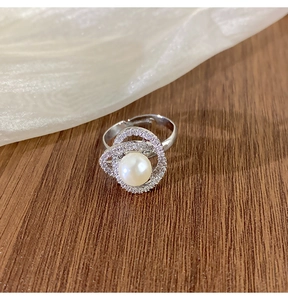 Vue détaillée de la bague en perle camélia avec zircons sur un fond en tissu doux