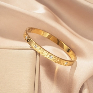 Goldener gehämmerter Edelstahl Armreif mit zehn funkelnden Kristallen und Verschluss