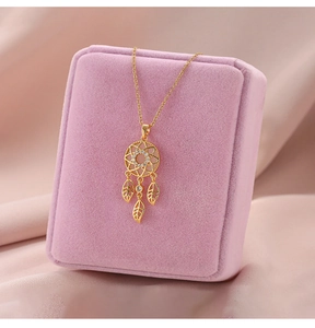Close-up of golden dreamcatcher necklace with zircon inlay on pink velvet box