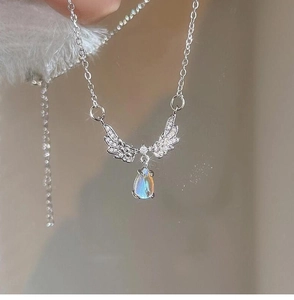 Macro detail of teardrop moonstone pendant with sparkling pavé crystal angel wings