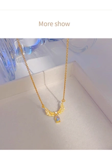 Close-up of gold angel wing necklace with moonstone drop on a white jewelry box