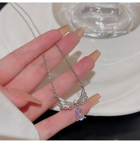 Detail of moonstone teardrop necklace with silver angel wings and diamond accents