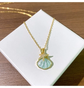 Détail du pendentif coquillage et étoile de mer doré avec paillettes bleues et zircons