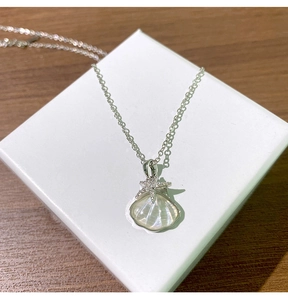 Détail d'un collier en titane argenté avec pendentifs coquillage et étoile de mer