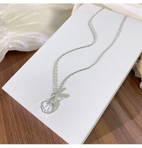 Détail du pendentif en forme de coquillage avec reflets irisés et petite étoile sertie