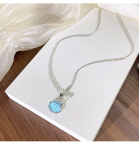 Détail du collier argenté avec pendentif coquillage bleu et étoile de mer sur tissu
