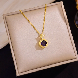 Detail van kroonvormige hanger met paarse zirkoon en gouden ketting op sieradendoos