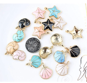 Detalle de dijes de esmalte de concha y estrella de mar con moneda para referencia de tamaño