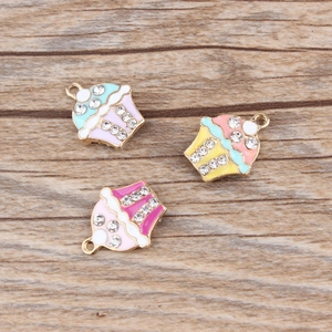 Gros plan détaillé de trois pendentifs cupcakes colorés avec strass pour création de bijoux DIY