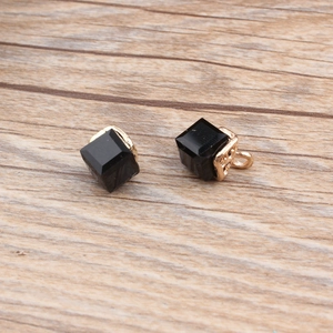 Detailed close-up of water cube crystal charms with gold hollow base on wood