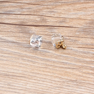 Detail of cube shaped transparent crystal pendants with golden alloy metal base on wood