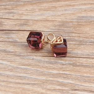 Detailed macro view of purple cube crystal pendants with golden filigree metal caps