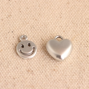 Detail of matte silver smiley face and 3D heart charms for DIY jewelry making