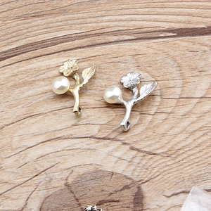 Macro detail of alloy flower pendants with white pearls in gold and silver finishes