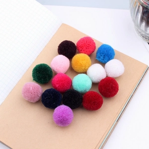 Mix of 20mm colorful cashmere pom-poms scattered on a notebook for DIY hair accessories