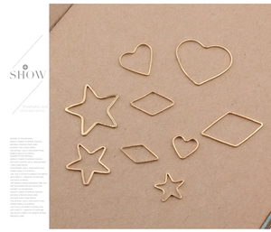 Macro view of assorted gold geometric DIY jewelry charms in star, heart, and rhombus shapes