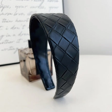 Detail of black woven leather headband with wide knotted design and premium texture