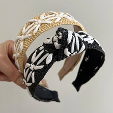 Close-up of beige and black braided headbands featuring intricate white embroidery patterns