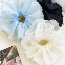 Close-up of three layered organza scrunchies in light blue, beige, and black colors