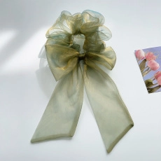 Detail of sage green organza scrunchie with long ribbons and a subtle pearlescent shimmer