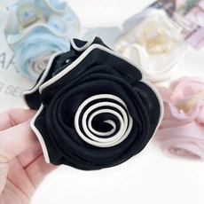 Detailed view of a fabric rose hair claw clip in black and white with a durable plastic base
