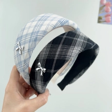 Detail of plaid wide headband with silver metal bow accent in blue and black pattern