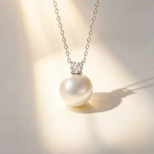 Macro detail of round freshwater pearl pendant with sparkling gemstone on silver chain